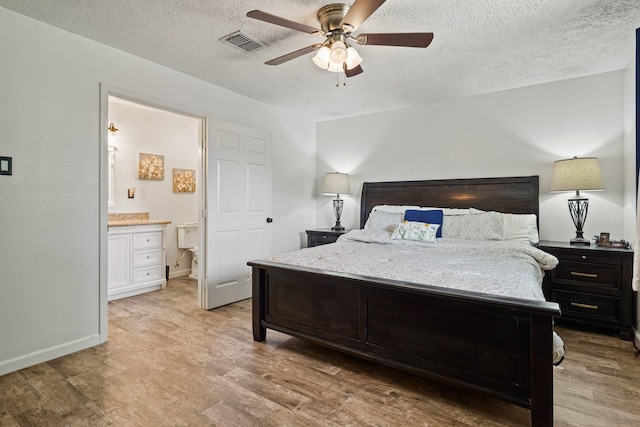 bedroom featuring light wood finished floors, visible vents, a textured ceiling, and connected bathroom