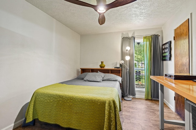 bedroom with baseboards, a ceiling fan, wood finished floors, and a textured ceiling