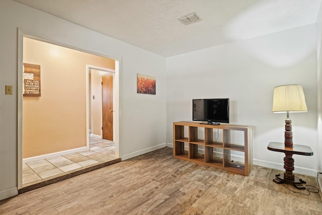 living area with visible vents, baseboards, and wood finished floors