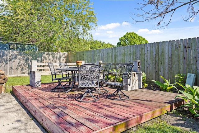 wooden deck with a fenced backyard and outdoor dining area