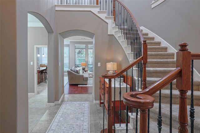 12203 Pinelands Park Ln, Humble, TX 77346 - tiled foyer featuring arched walkways, baseboards, stairway, and crown molding