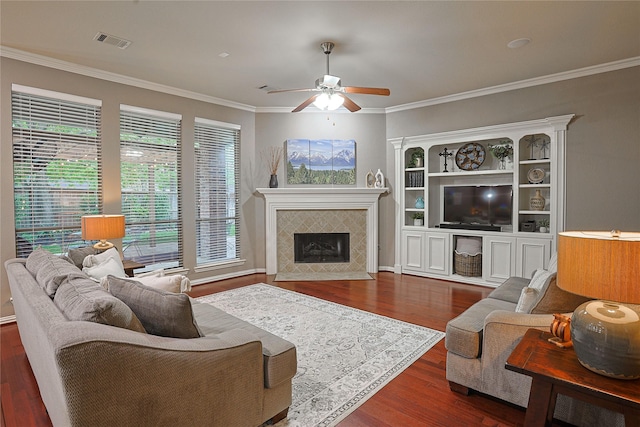 12203 Pinelands Park Ln, Humble, TX 77346 - living area with a ceiling fan, dark wood-type flooring, a tiled fireplace, and crown molding