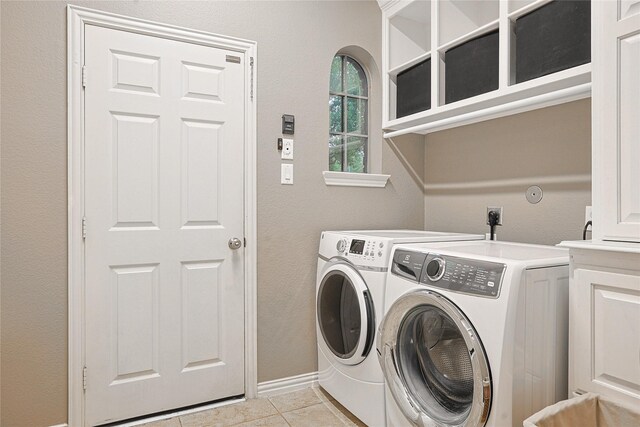 12203 Pinelands Park Ln, Humble, TX 77346 - washroom featuring separate washer and dryer, light tile patterned flooring, cabinet space, baseboards, and a textured wall