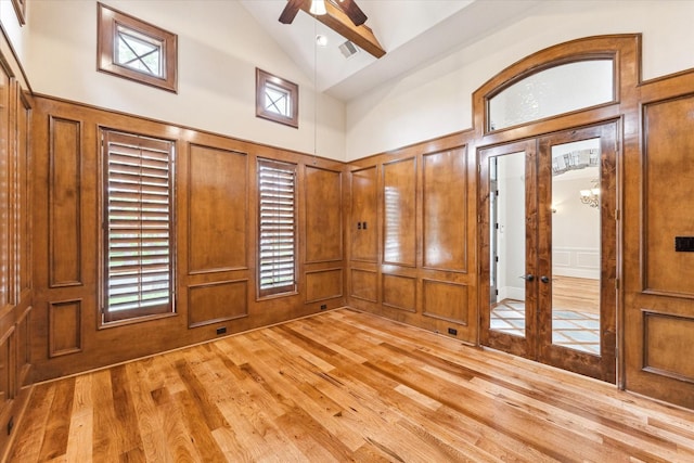 entrance foyer with light wood-style floors, french doors, a decorative wall, a ceiling fan, and high vaulted ceiling
