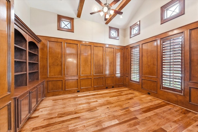 interior space with light wood-type flooring, high vaulted ceiling, a ceiling fan, and a decorative wall