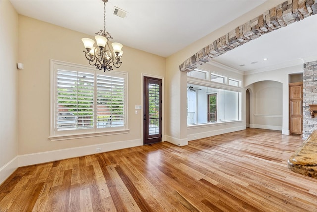 interior space with visible vents, baseboards, arched walkways, light wood-type flooring, and a notable chandelier