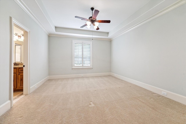 unfurnished room with light colored carpet, a raised ceiling, a ceiling fan, and baseboards