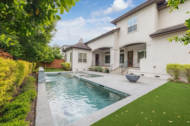 rear view of house featuring stucco siding, a patio, an in ground hot tub, and a fenced in pool