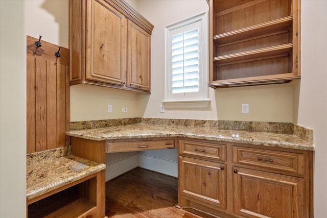 interior space with light stone countertops, open shelves, and wood finished floors