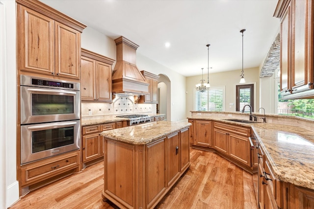 kitchen with decorative backsplash, appliances with stainless steel finishes, light wood finished floors, and a sink