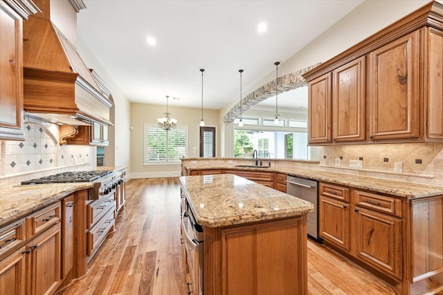 kitchen with brown cabinets, a notable chandelier, a sink, and appliances with stainless steel finishes