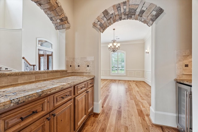 interior space with beverage cooler, french doors, an inviting chandelier, ornamental molding, and wood finished floors