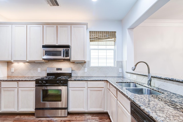 5976 Kansas St, Houston, TX 77007 - kitchen featuring appliances with stainless steel finishes, a sink, light stone counters, backsplash, and crown molding