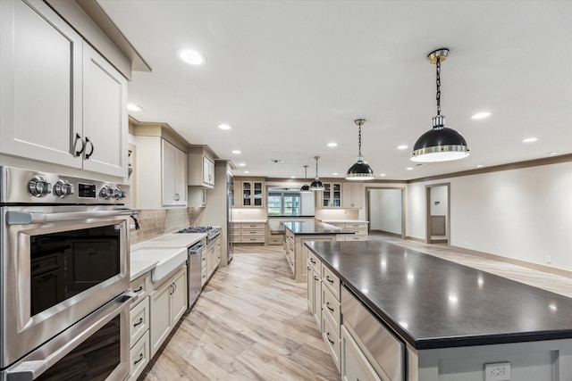 5807 Lilac St, Katy, TX 77493 - kitchen with light wood-style floors, tasteful backsplash, dark countertops, stainless steel double oven, and a spacious island