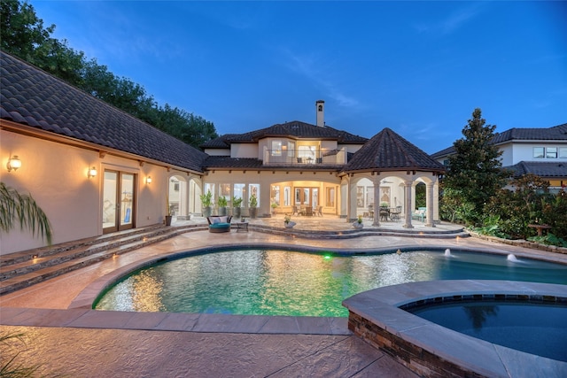 pool featuring french doors, a patio area, and an in ground hot tub