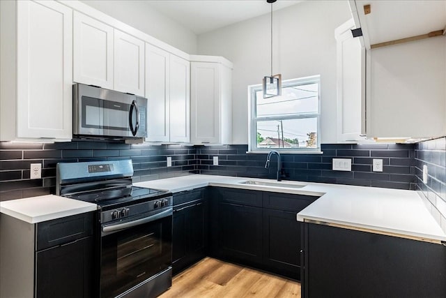 kitchen with a sink, tasteful backsplash, light wood-type flooring, and stainless steel appliances