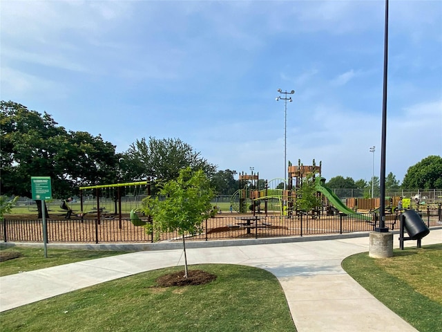 view of property's community with fence, playground community, and a yard