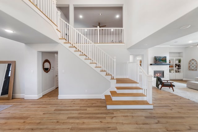 10593 Lake Palmetto Dr, Conroe, TX 77385 - staircase with ceiling fan, a high ceiling, wood finished floors, baseboards, and a fireplace