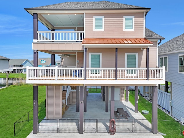 back of house with a shingled roof, a carport, a patio area, a lawn, and fence