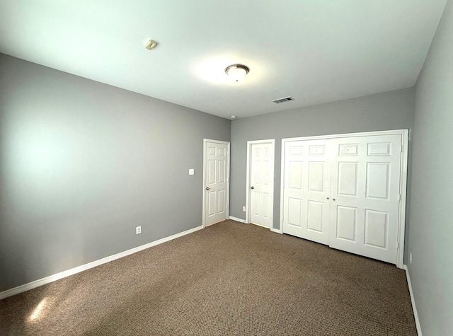 unfurnished bedroom featuring dark carpet, visible vents, and baseboards