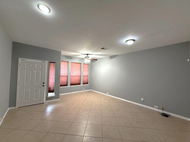 spare room with light tile patterned floors, baseboards, a ceiling fan, and visible vents