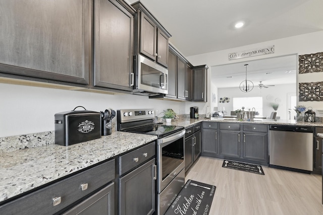 11034 Hillside Creek Dr, Humble, TX 77396 - kitchen featuring dark brown cabinets, light stone counters, a sink, stainless steel appliances, and light wood finished floors