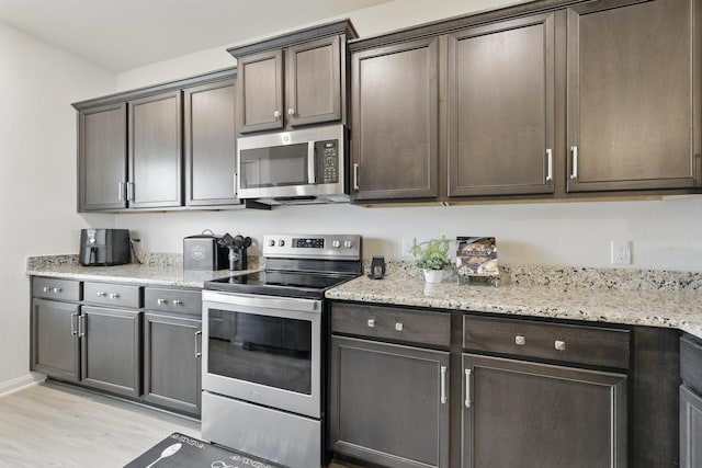 11034 Hillside Creek Dr, Humble, TX 77396 - kitchen featuring baseboards, light wood-style flooring, dark brown cabinets, light stone countertops, and appliances with stainless steel finishes