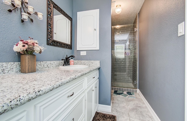 bathroom with a stall shower, baseboards, and vanity