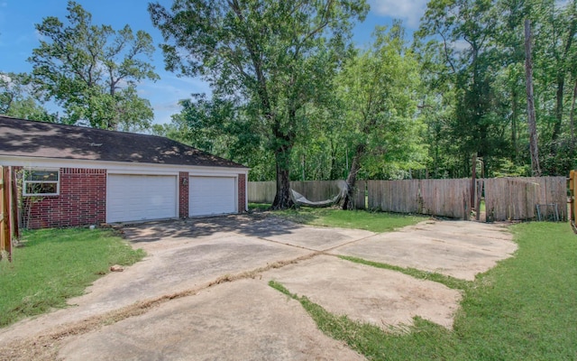 view of yard featuring concrete driveway, fence, and a garage