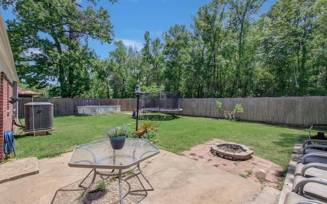 view of patio with a fenced backyard, a trampoline, central AC unit, and an outdoor fire pit