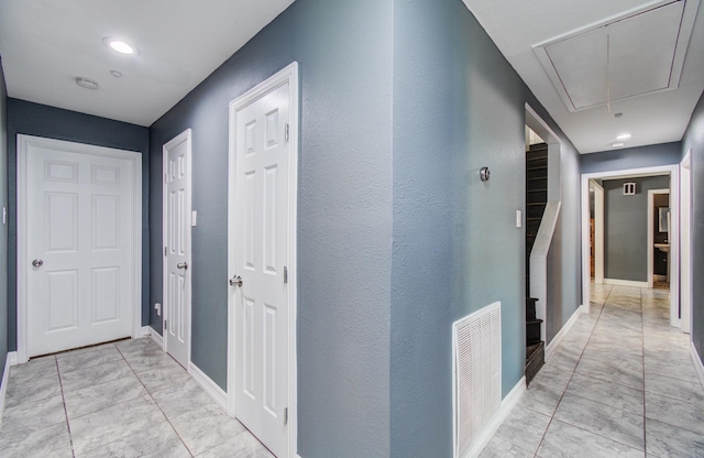 hallway with visible vents, attic access, baseboards, and marble finish floor