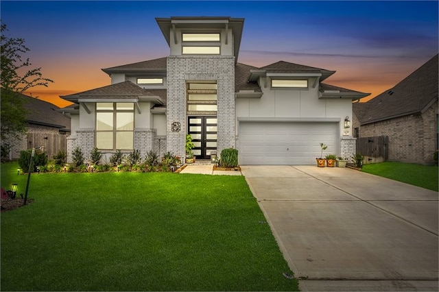 prairie-style home featuring a garage, a front yard, brick siding, a shingled roof, and concrete driveway