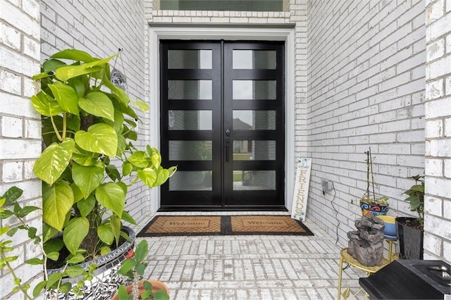 view of exterior entry featuring brick siding and french doors