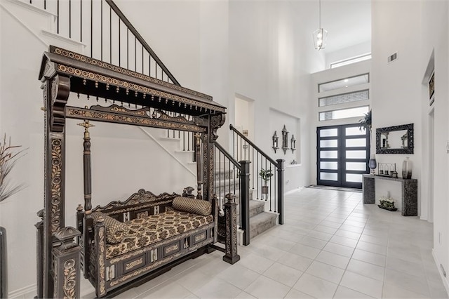 entryway featuring visible vents, tile patterned floors, a high ceiling, and stairs