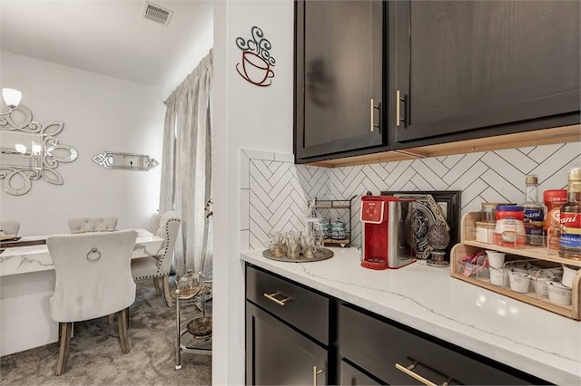 kitchen featuring tasteful backsplash, visible vents, a notable chandelier, and light stone counters