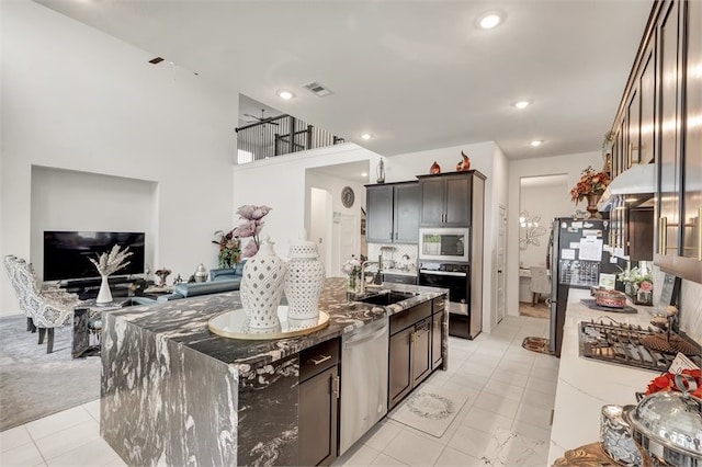 kitchen with visible vents, a sink, appliances with stainless steel finishes, an island with sink, and stone counters