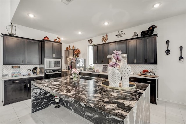 kitchen featuring dark stone counters, appliances with stainless steel finishes, light tile patterned floors, and a sink
