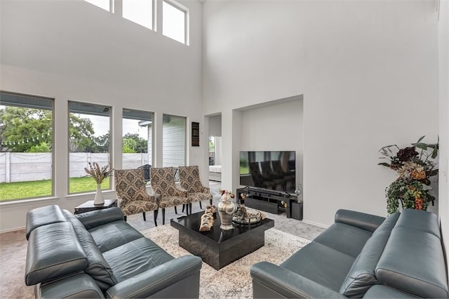 carpeted living area featuring a towering ceiling and baseboards