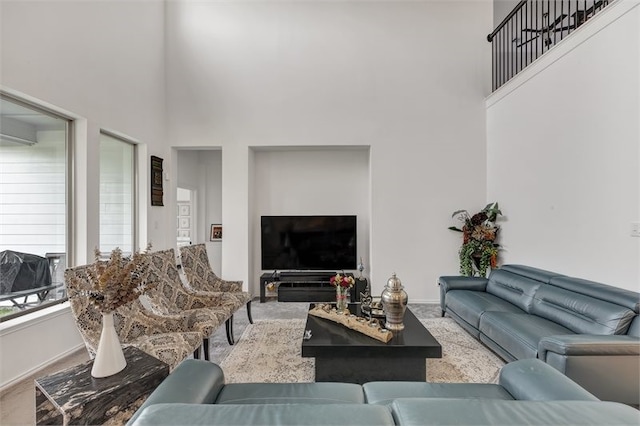 living area with a high ceiling, baseboards, and carpet floors