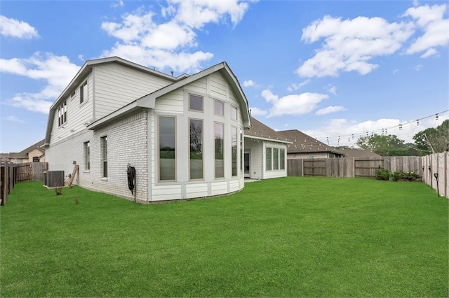 back of property featuring a yard, brick siding, a fenced backyard, and cooling unit