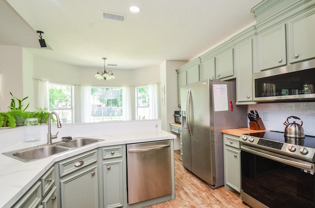 kitchen featuring stainless steel appliances, a sink, plenty of natural light, and a chandelier