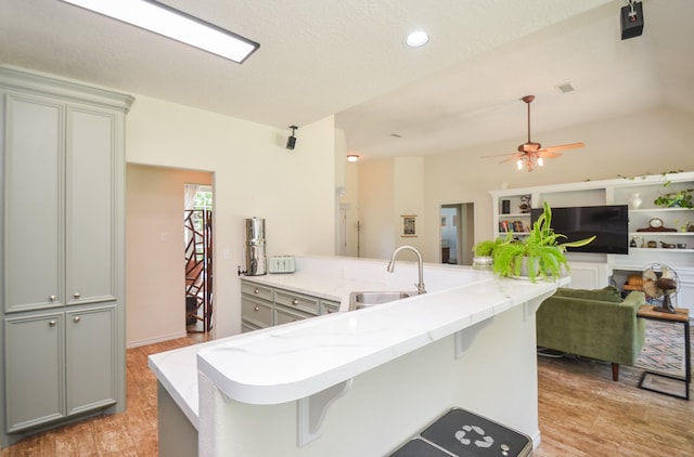 kitchen featuring a sink, light wood-style flooring, light stone counters, a breakfast bar, and recessed lighting