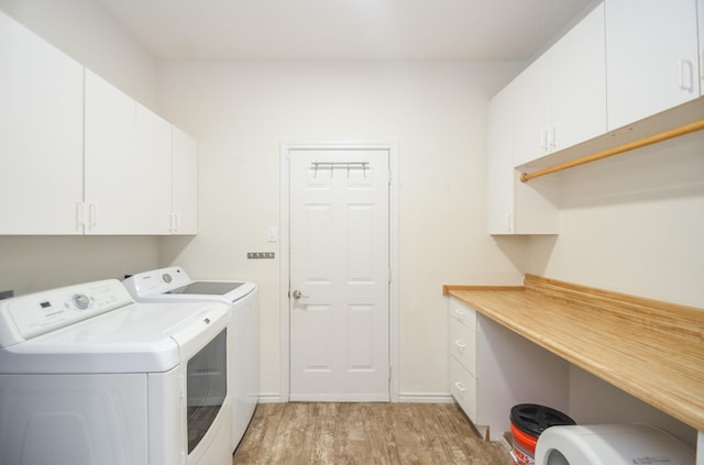 washroom with cabinet space, washing machine and dryer, light wood-type flooring, and baseboards
