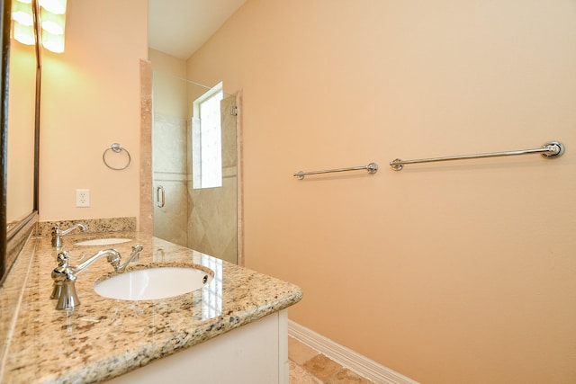 full bathroom with a shower with door, vanity, and baseboards