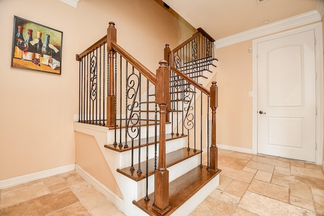stairway with stone tile floors, baseboards, and ornamental molding