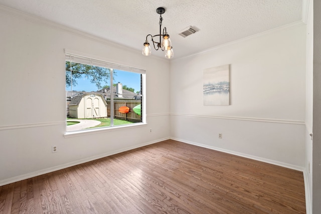 unfurnished room with wood finished floors, baseboards, visible vents, a textured ceiling, and crown molding