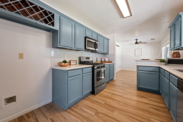 kitchen with tasteful backsplash, blue cabinets, appliances with stainless steel finishes, light wood-type flooring, and a ceiling fan