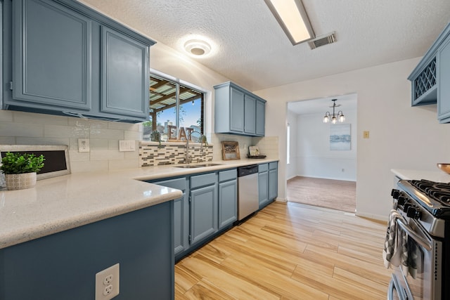 kitchen with appliances with stainless steel finishes, visible vents, blue cabinets, and a sink