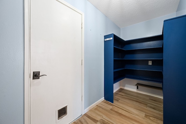 interior space with a textured ceiling, visible vents, wood finished floors, and baseboards