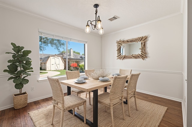 dining space featuring visible vents, wood finished floors, an inviting chandelier, and crown molding